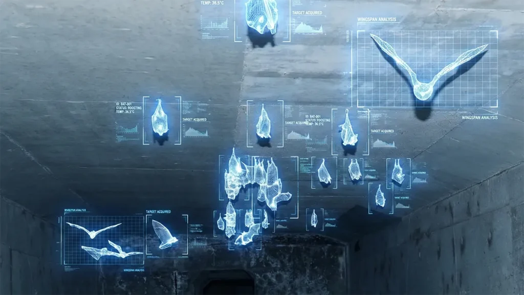 コウモリの臭い・匂いは情報の記憶だった|なぜ毎日糞掃除しても戻るのか?論文から紐解く理由と対策 35 コンクリート造りの地下空間の天井に、複数のコウモリがとまったり飛翔したりしている様子。それぞれのコウモリが青いワイヤーフレームで強調され、周囲には「WINGSPAN ANALYSIS」や「TARGET ACQUIRED」といった文字やグラフなどの解析データがホログラムのように表示されており、生態を高度な技術でモニタリングしている状態を表現したイメージ画像。